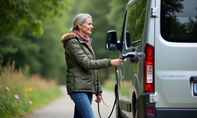 Femme souriante près d’un van électrique en forêt