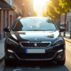 Voiture Peugeot 308 2015 stationnee en ville en plein soleil