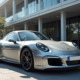 Porsche 911 argentée devant un bâtiment moderne ensoleillé